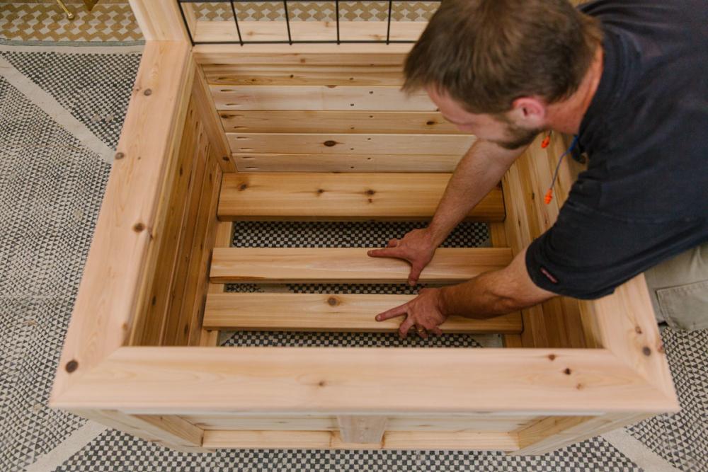 Placing boards in the bottom of the planter box of the wooden DIY deck privacy screen.