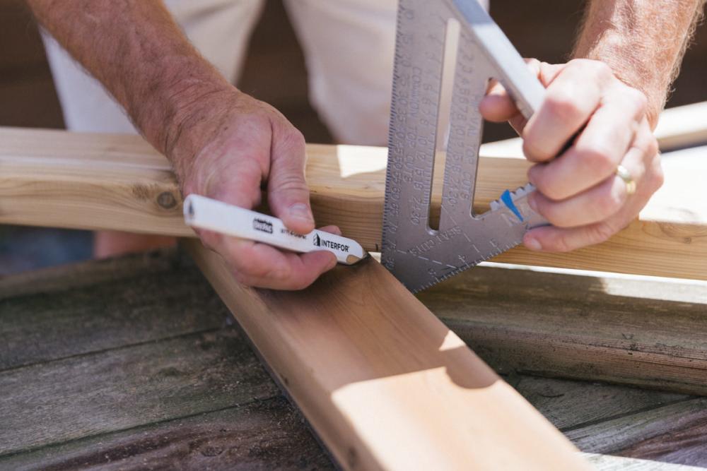 Laying a new board for the Z-frame over the old board and marking it with a speed square and a pencil.