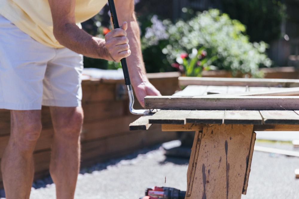 Using a pry bar to remove old fence boards from Z-frame.