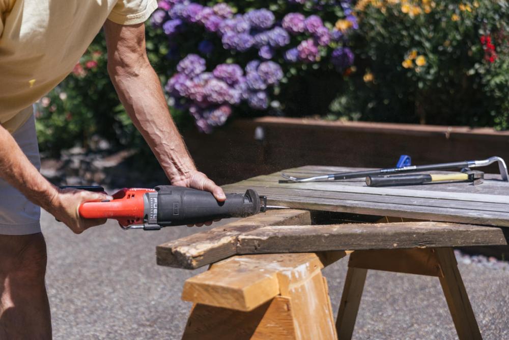 Using a sawzall to remove old fence boards, which are now clamped to a sawhorse, from Z-frame.