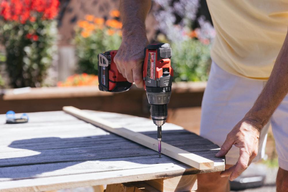 Using an extra board to ensure screws attaching fence boards to Z-frame are in a straight line. 