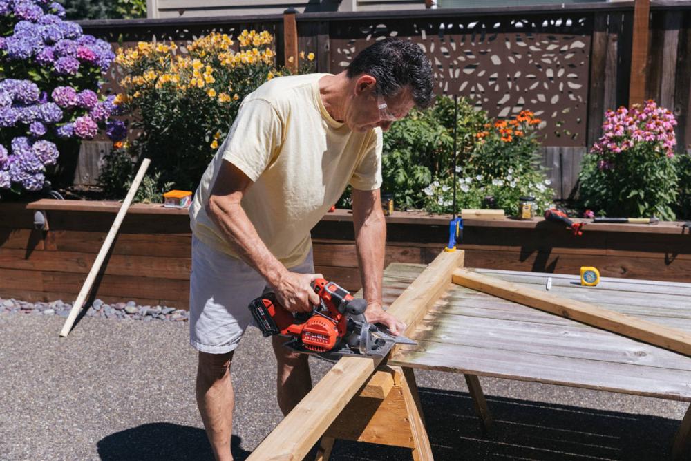 Using a circular saw to cut a cedar board into a vertical brace for the fence gate.