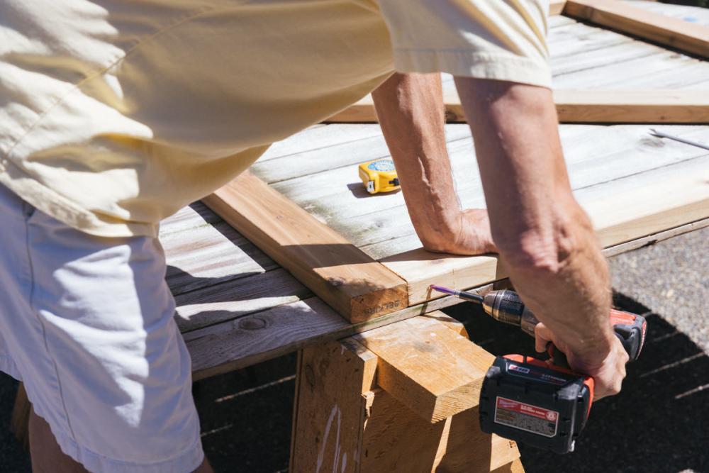 Using a drill to attach the vertical braces to the fence gate.