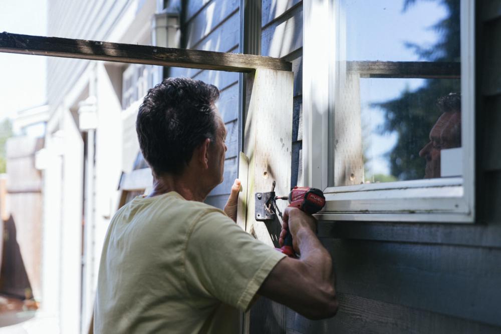 Using a drill to detach the latch on the fence frame.