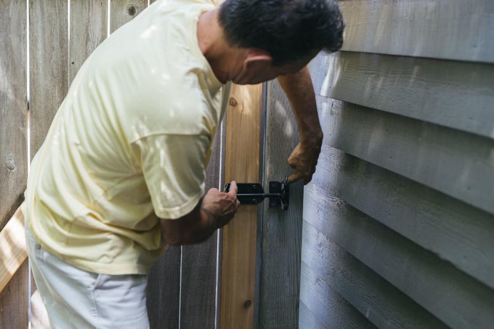 Holding the fence gate with the latch post against the latch to determine new placement. 