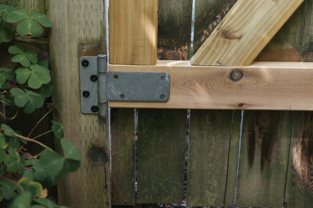 Close-up on the hinge of the fence gate, moved to avoid the sheared screws from the previous hinge placement.