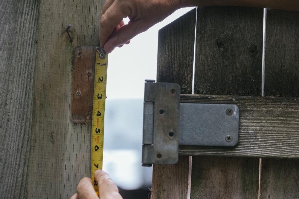Using a tape measure where the hinge of the fence gate has been removed.