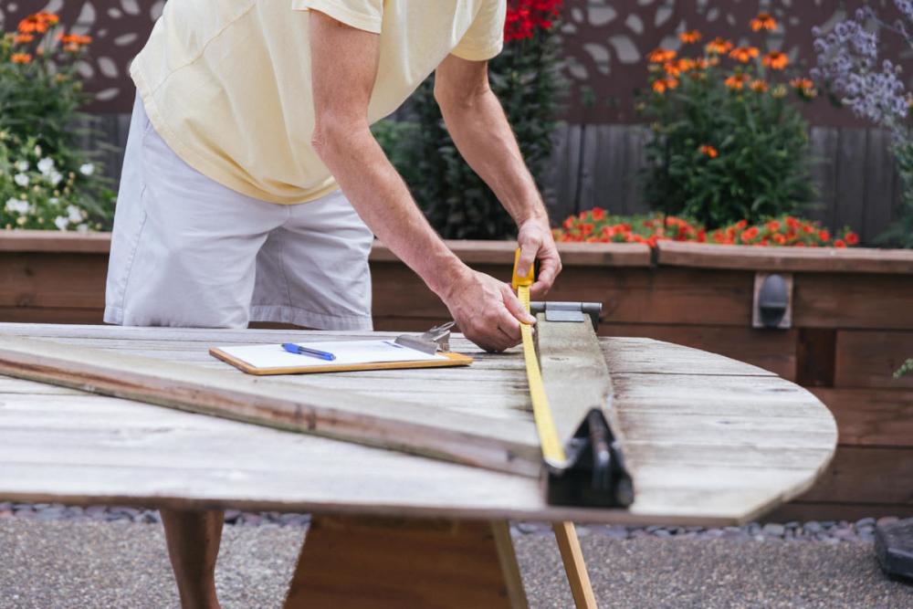 Using a tape measure to measure the Z-frame of the fence gate.