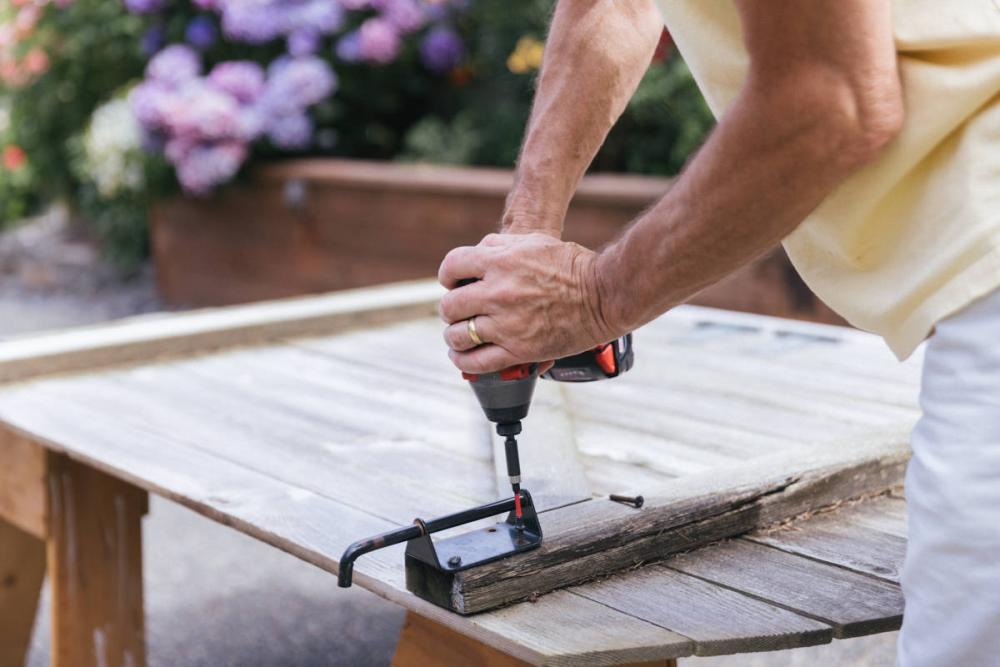 Using a drill to remove the latch from the fence gate.
