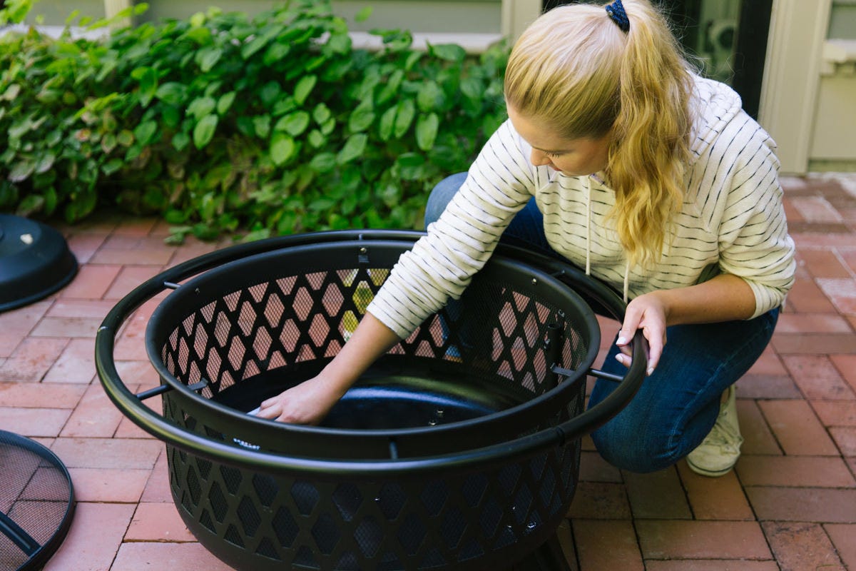 Wiping inside of fire pit with canola oil.