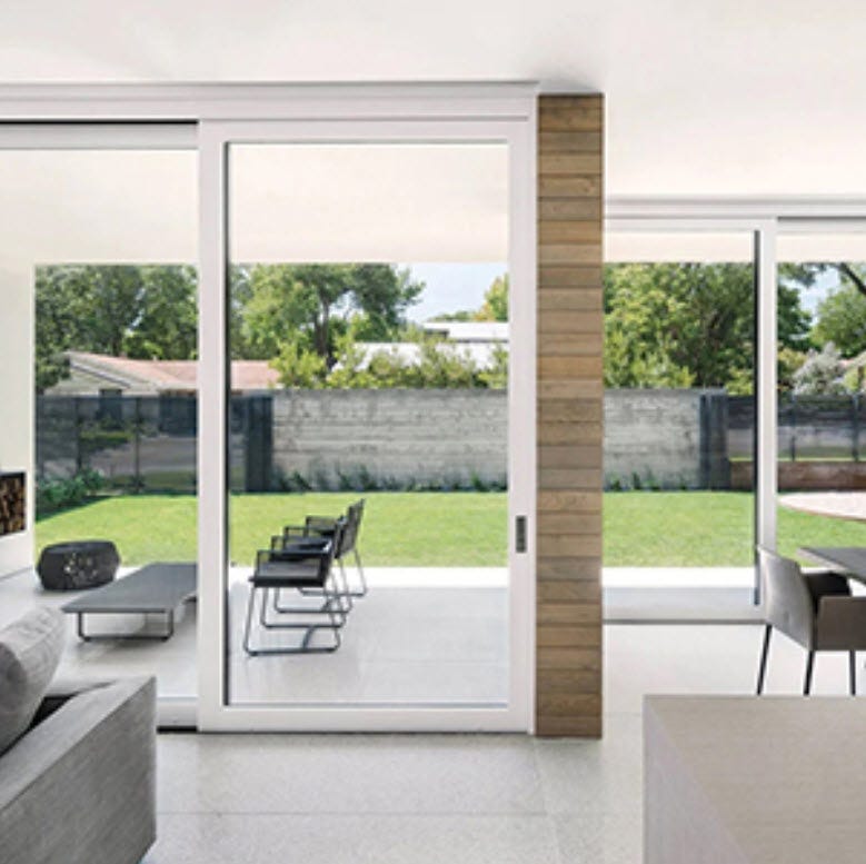 A modern room with two multi-slide doors facing exterior lawn and garden area.