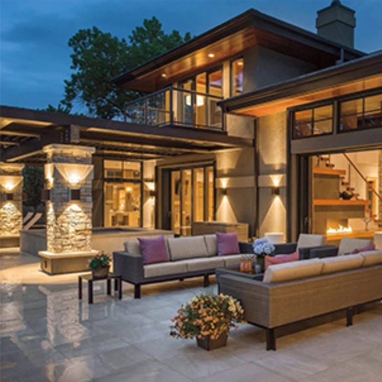 An exterior recreation area of house with two slide doors open to a warm interior.